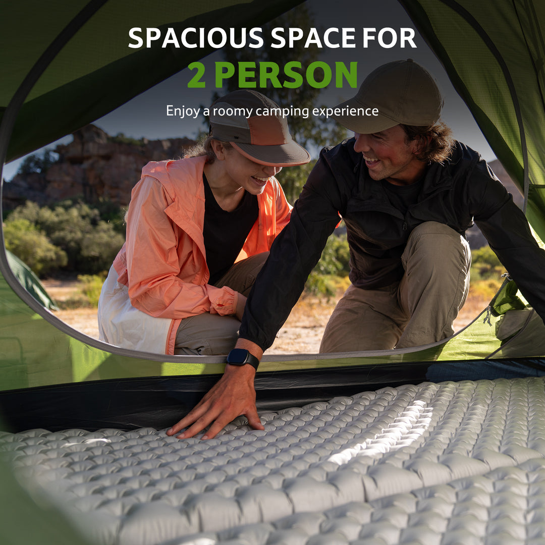 Two campers arranging sleeping mats inside a green Bleik 2-Person Backpacking Tent, showing spacious interior and comfortable two-person camping experience. Lightweight freestanding double wall tent for hiking, backpacking, trekking, and bikepacking adventures. Durable 210T tear-resistant polyester, PU3000mm+ waterproof, wind-resistant frame, roomy interior for gear and sleeping, portable and compact for multi-day outdoor trips.