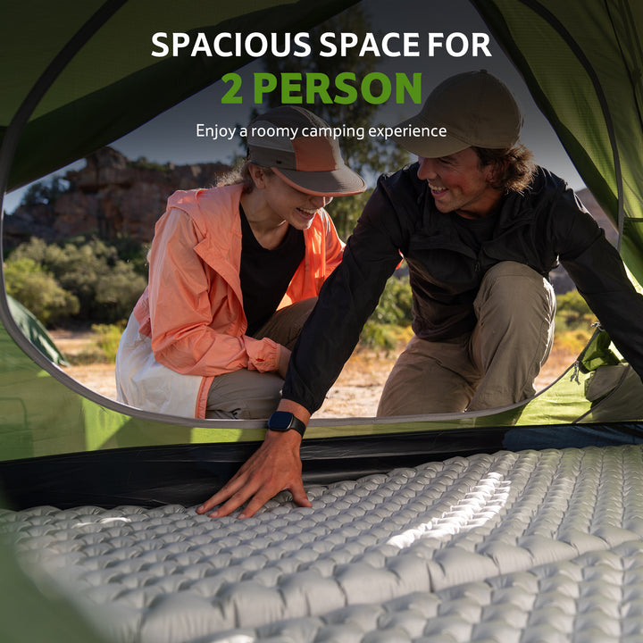 Two campers arranging sleeping mats inside a green Bleik 2-Person Backpacking Tent, showing spacious interior and comfortable two-person camping experience. Lightweight freestanding double wall tent for hiking, backpacking, trekking, and bikepacking adventures. Durable 210T tear-resistant polyester, PU3000mm+ waterproof, wind-resistant frame, roomy interior for gear and sleeping, portable and compact for multi-day outdoor trips.