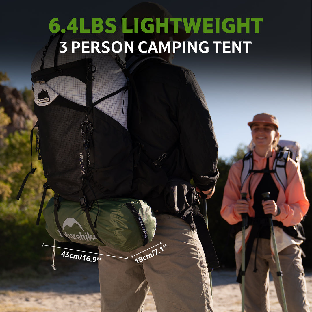 Bleik 3-Person Backpacking Tent in green shown in outdoor hiking scene: two hikers carrying the tent compactly strapped to their backpacks, highlighting its lightweight, small packed size and easy portability for trekking and camping.