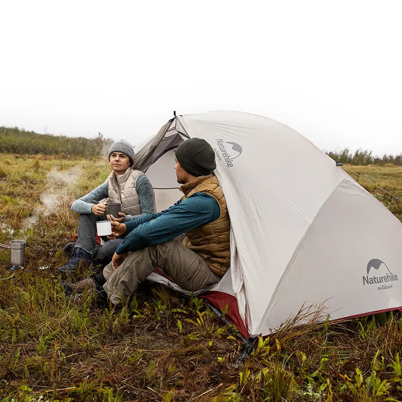 Hikers enjoying the moment while setting up the Naturehike Star-River 4-Season Tent against a backdrop of majestic mountains. The scene emphasizes the tent's ease of setup and reliable protection for alpine and challenging outdoor adventures.