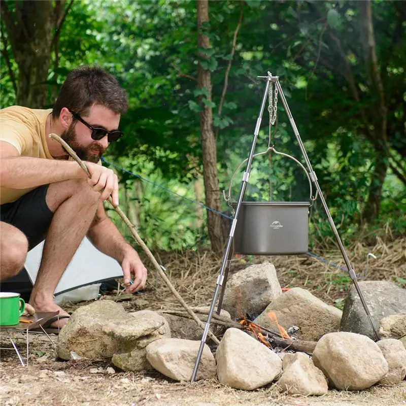 The 4-6 Persons Aluminum Alloy Hanging Pot in an authentic outdoor setting, suspended over a campfire or stove, demonstrating its practical hanging design for versatile and convenient camp cooking.